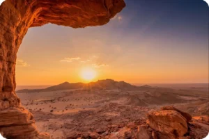 Sunset framed by a natural rock overhang in the Tuwaiq Mountains