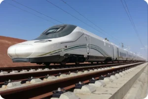 Haramain train traveling on railway tracks under a clear Saudi sky