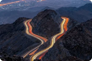 Vehicle light trails along a winding road through Al Hada’s mountains