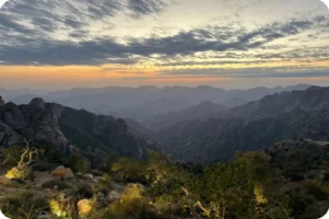 Mountain ridges and green slopes beneath a cloudy sky in Al Shafa