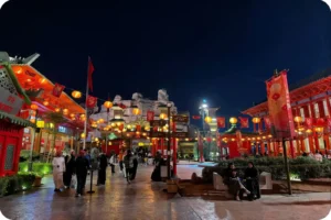 Visitors walking through a brightly lit entertainment district with colourful buildings.