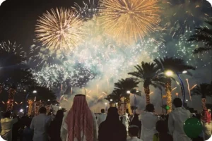 Crowd watching golden fireworks above an outdoor entertainment venue.